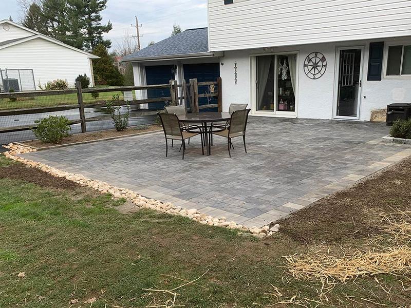 grey backyard hardscaped patio lined with rocks
